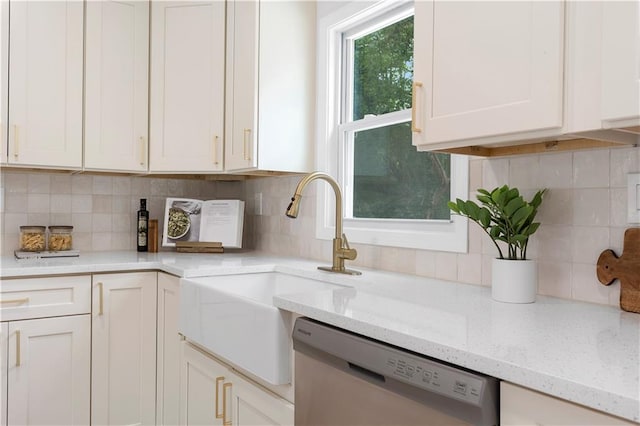 kitchen featuring white cabinetry, dishwasher, light stone countertops, sink, and backsplash