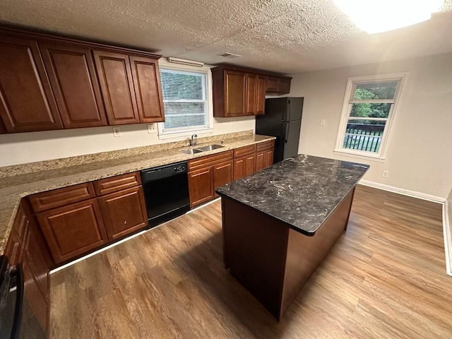 1095 S Burnt Hickory Rd, Douglasville, GA 30134 - kitchen with black appliances, wood finished floors, a textured ceiling, a sink, and a center island