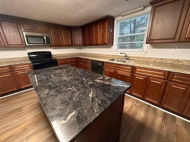 1095 S Burnt Hickory Rd, Douglasville, GA 30134 - kitchen featuring black appliances, a sink, light wood finished floors, a kitchen island, and a textured ceiling