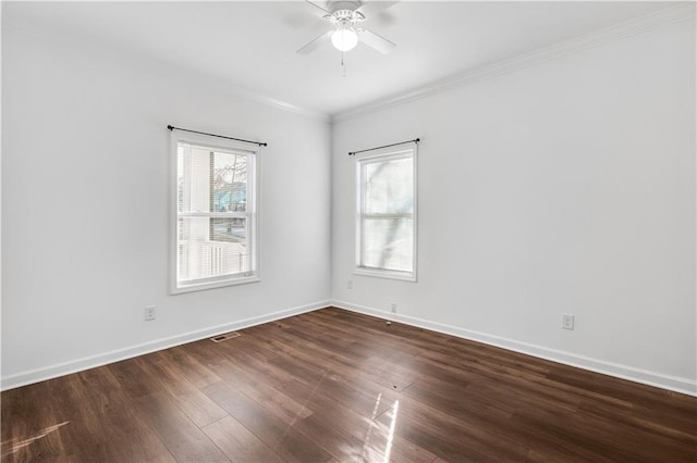 empty room featuring dark wood-style flooring, visible vents, crown molding, and baseboards