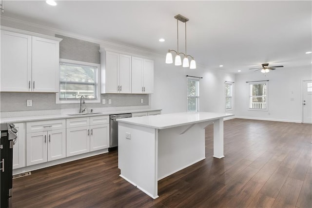 kitchen with dishwasher, light countertops, hanging light fixtures, and a sink