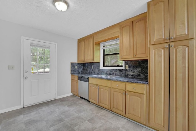 kitchen with stainless steel dishwasher, a sink, dark countertops, decorative backsplash, and baseboards