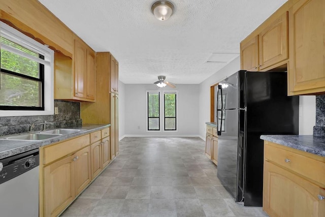 kitchen with stainless steel dishwasher, a sink, freestanding refrigerator, a textured ceiling, and tasteful backsplash