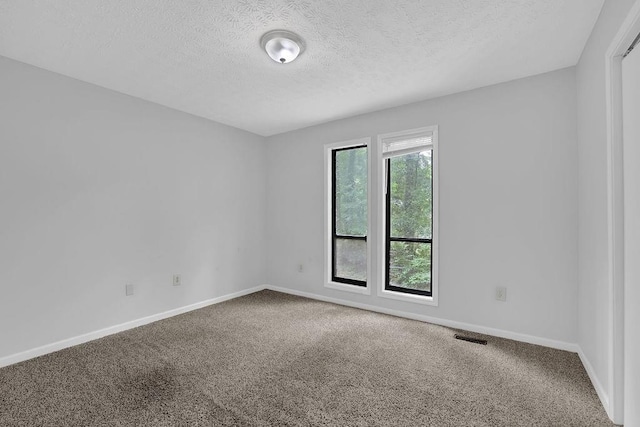 spare room with carpet floors, a textured ceiling, and baseboards