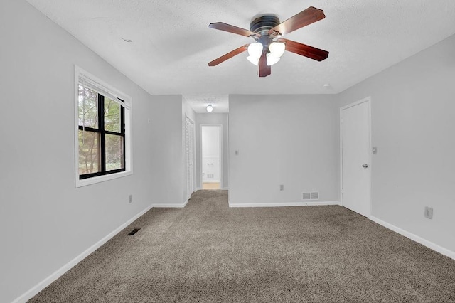 carpeted empty room featuring ceiling fan, a textured ceiling, and baseboards