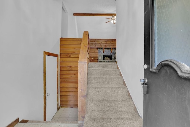 stairs with a ceiling fan, tile patterned flooring, and a fireplace