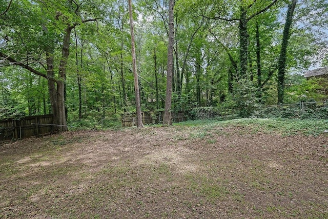 view of yard with fence and a wooded view