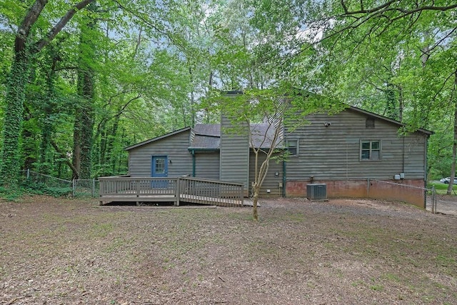 rear view of house featuring central air condition unit, a deck, fence, and a chimney