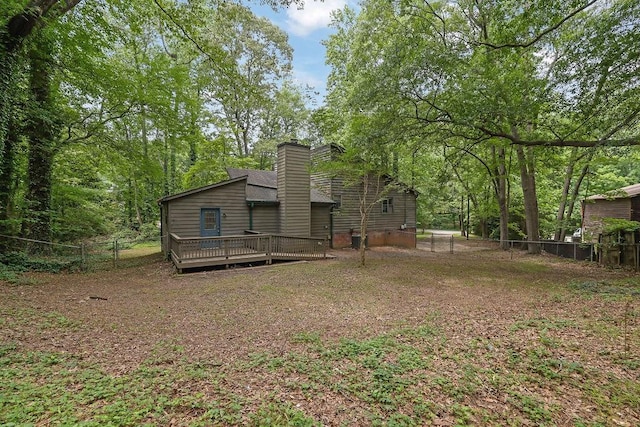 back of property featuring a wooden deck, fence, and a chimney