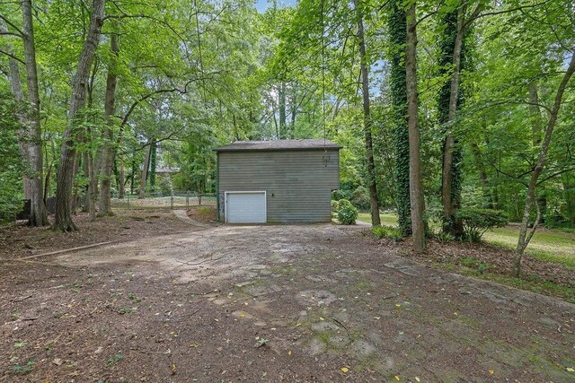 view of yard with an outdoor structure, a garage, and dirt driveway