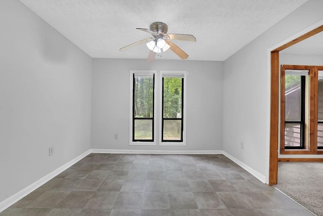 spare room featuring a ceiling fan, a textured ceiling, and baseboards
