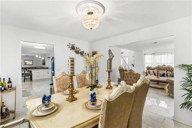 dining space featuring a notable chandelier, marble finish floor, stairs, and a textured ceiling