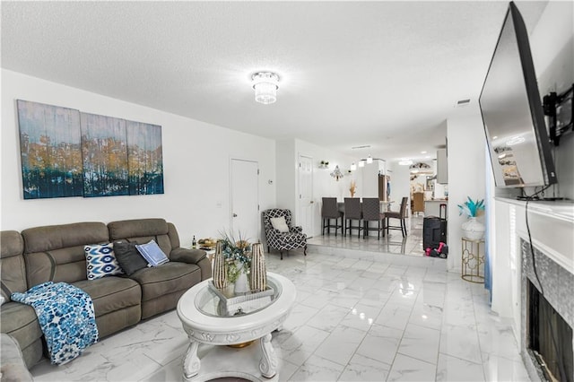 living room featuring a textured ceiling, marble finish floor, and a fireplace