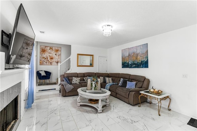 living area featuring visible vents, marble finish floor, a textured ceiling, a high end fireplace, and baseboards