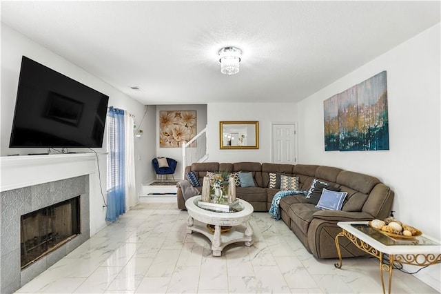 living room with visible vents, marble finish floor, a fireplace, and a textured ceiling