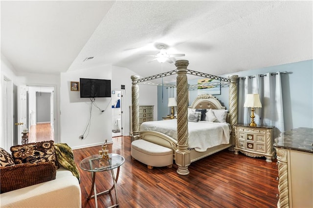 bedroom with a ceiling fan, visible vents, dark wood finished floors, vaulted ceiling, and a textured ceiling