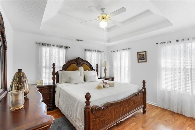 bedroom featuring visible vents, a tray ceiling, and wood finished floors