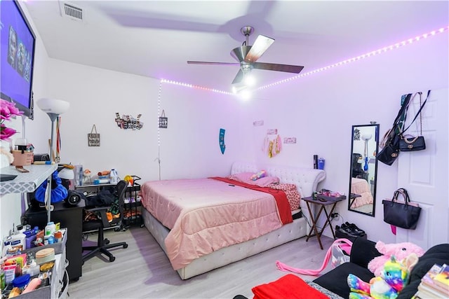 bedroom with wood finished floors, visible vents, and ceiling fan