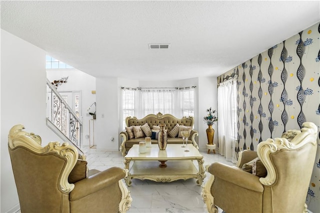 living room featuring stairs, visible vents, marble finish floor, and a textured ceiling