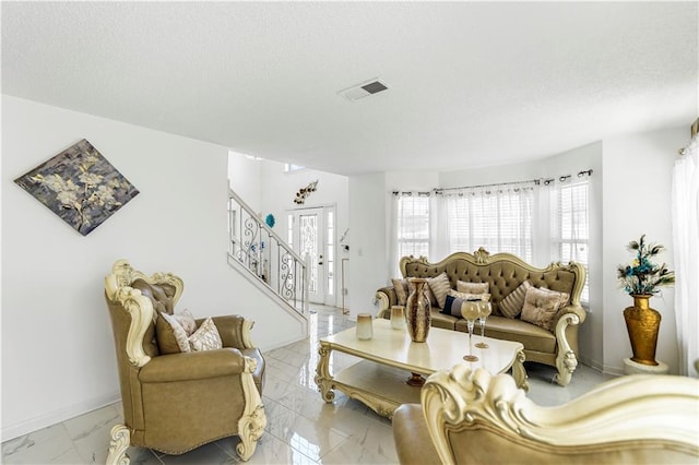 living room with visible vents, stairway, a textured ceiling, and baseboards