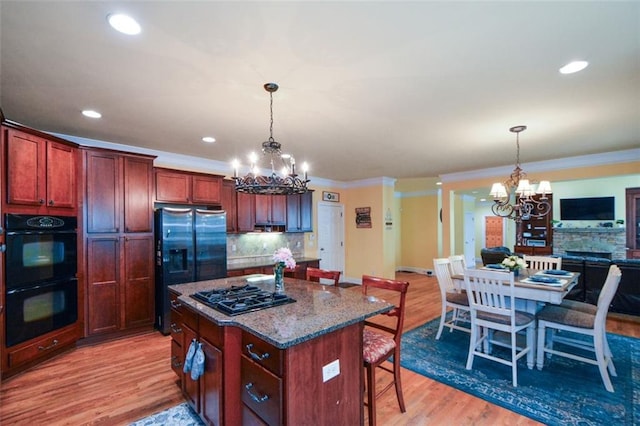 3423 Mulberry Lane Ct, Dacula, GA 30019 - kitchen featuring a chandelier, black appliances, a breakfast bar, tasteful backsplash, and light wood-type flooring
