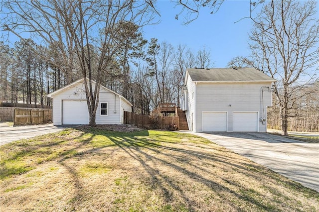 view of property exterior featuring a yard, a garage, and fence