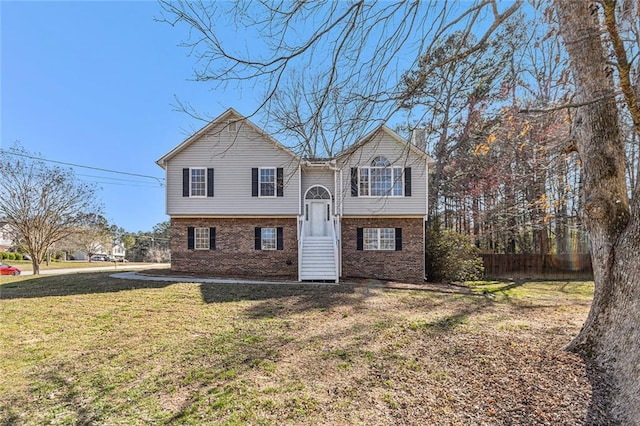 bi-level home featuring brick siding, a front lawn, and fence