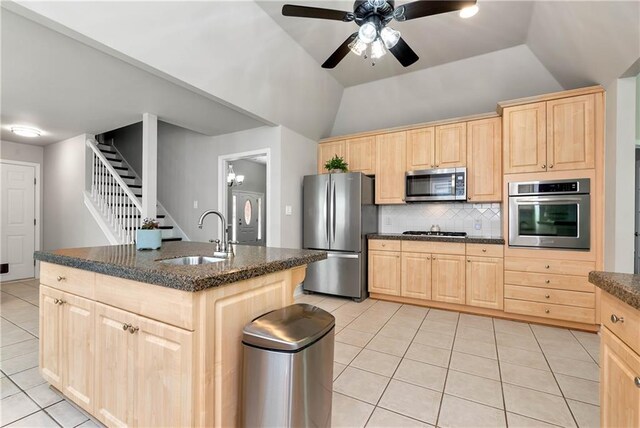 kitchen with appliances with stainless steel finishes, light brown cabinetry, a sink, light tile patterned floors, and vaulted ceiling