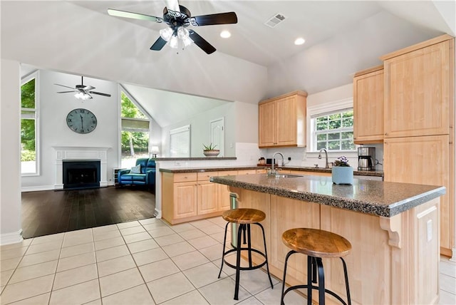 kitchen featuring light brown cabinetry, a sink, lofted ceiling, ceiling fan, and open floor plan