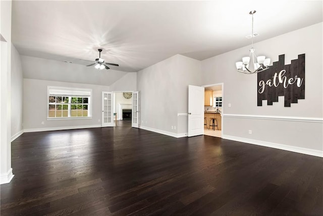 unfurnished living room featuring a chandelier, ceiling fan, dark wood-type flooring, baseboards, and vaulted ceiling