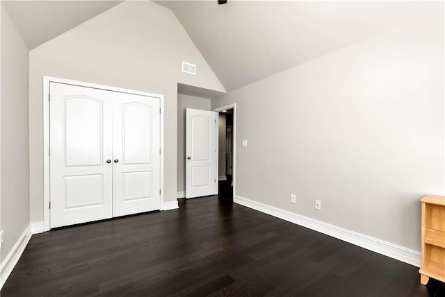 unfurnished bedroom with baseboards, dark wood finished floors, a closet, and high vaulted ceiling