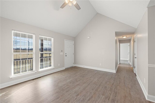 unfurnished living room with ceiling fan with notable chandelier, dark wood-type flooring, and vaulted ceiling