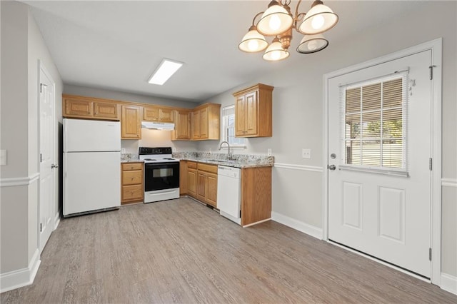 kitchen featuring white appliances, a sink, light wood-style floors, under cabinet range hood, and a wealth of natural light