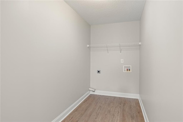 laundry area with laundry area, electric dryer hookup, baseboards, and wood finished floors