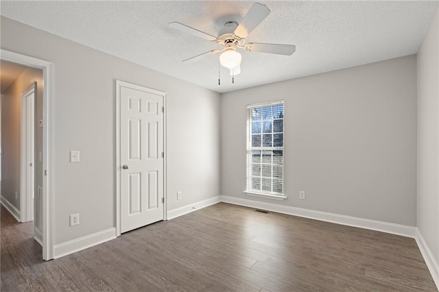 spare room featuring ceiling fan, baseboards, a textured ceiling, and dark wood finished floors