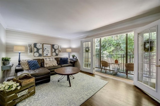 living room featuring wood-type flooring, ornamental molding, and wooden walls