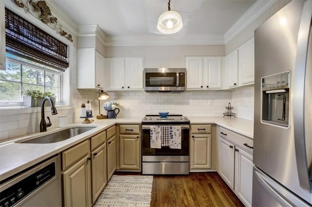 kitchen featuring sink, appliances with stainless steel finishes, decorative light fixtures, white cabinets, and ornamental molding