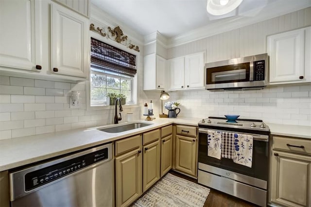 kitchen with tasteful backsplash, stainless steel appliances, crown molding, sink, and white cabinets