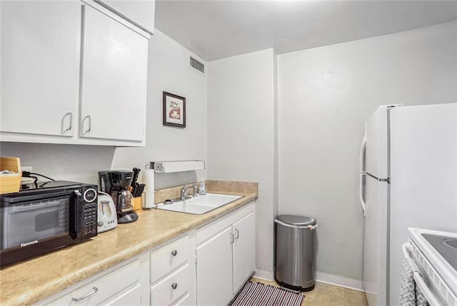 kitchen featuring electric range oven, white cabinetry, sink, white fridge, and light tile patterned floors