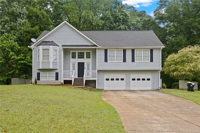 raised ranch featuring roof with shingles, an attached garage, a front lawn, and driveway