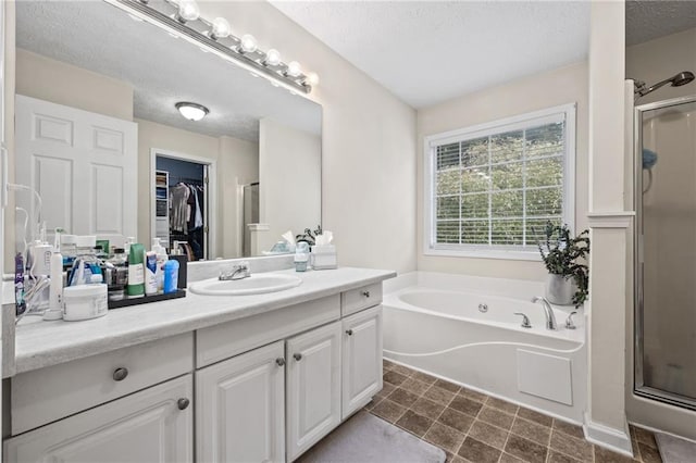 bathroom featuring vanity, a textured ceiling, a stall shower, a spacious closet, and a bath
