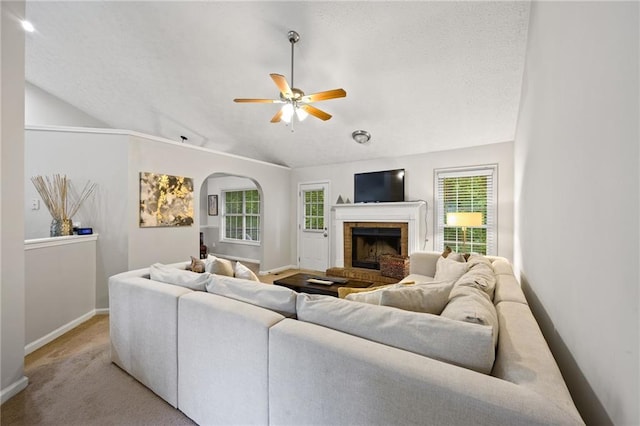 living area with ceiling fan, vaulted ceiling, baseboards, and a healthy amount of sunlight