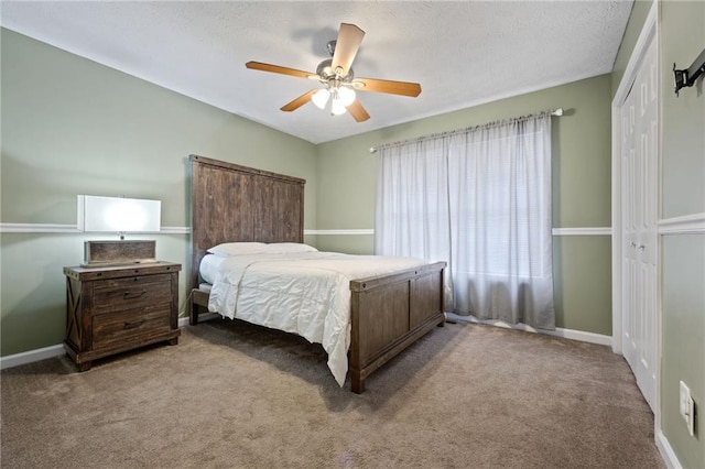 bedroom featuring a closet, a textured ceiling, ceiling fan, carpet floors, and baseboards
