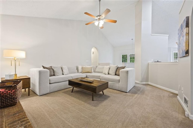 carpeted living area with visible vents, baseboards, ceiling fan, and high vaulted ceiling