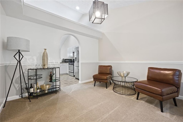 sitting room featuring light carpet, baseboards, and arched walkways