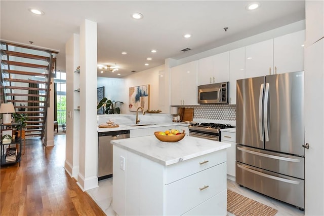 kitchen featuring a sink, stainless steel appliances, white cabinetry, tasteful backsplash, and visible vents