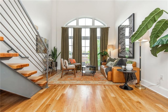 living area featuring baseboards, stairs, a towering ceiling, and wood finished floors