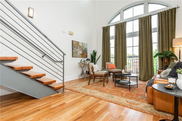sitting room with baseboards, a high ceiling, stairs, and wood finished floors