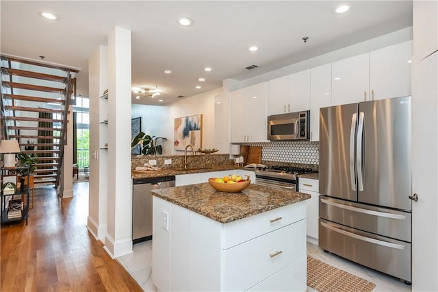 kitchen featuring visible vents, a sink, dark stone countertops, appliances with stainless steel finishes, and backsplash