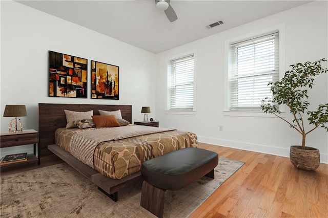 bedroom with visible vents, baseboards, ceiling fan, and wood finished floors